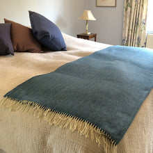 Sky blue herringbone wool throw folded up at the end of a double bed