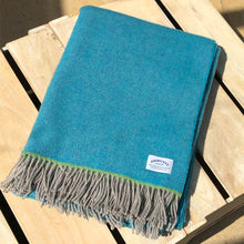 Turquoise wool throw folded on a wooden box