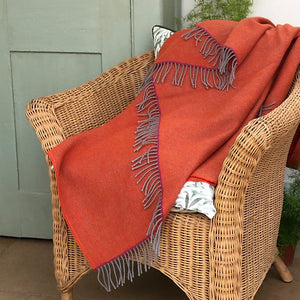 Orange wool blanket thrown over a wicker chair