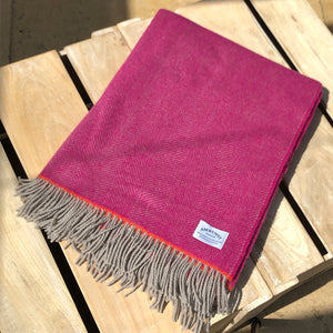 Pink wool throw blanket folded on a wooden box