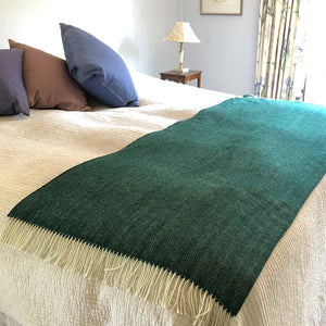 Spruce herringbone wool throw folded up over the bottom of a bed