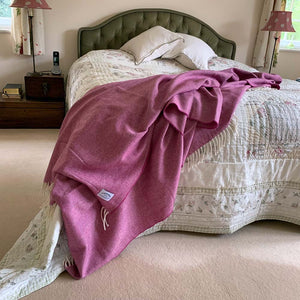 Mulberry pink interior throw thrown on end of a double bed