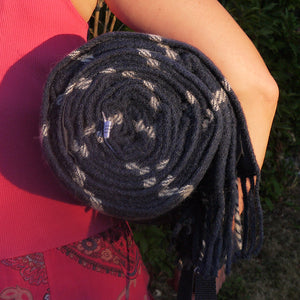 Navy blue and white waterproof wool picnic blanket rolled up and being carried by a young lady.