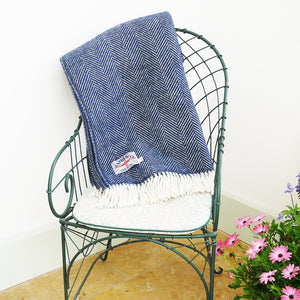 dark blue herringbone throw folded over the back of an iron chair