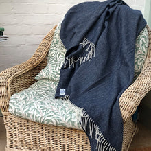 Navy herringbone wool blanket thrown over a wicker chair