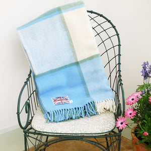 Sea cream blue pure wool check throw folded up over the back of a chair in the conservatory.