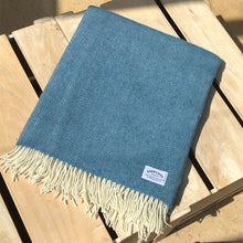 Sky blue herringbone wool throw folded up on a wooden box