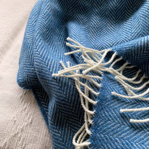 White tassels on the edge of a light blue wool throw